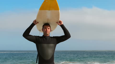 Confident Surfer Holding Board in Front of Ocean Waves