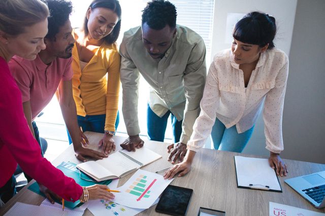Group of diverse coworkers collaborating on a project in a modern office. Ideal for illustrating teamwork, corporate culture, and collaborative work environments. Useful for business presentations, corporate websites, and articles on workplace diversity and inclusion.