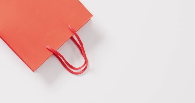 Orange gift bag with string handles on white background with copy space. Shopping, sale and retail concept digitally generated image.