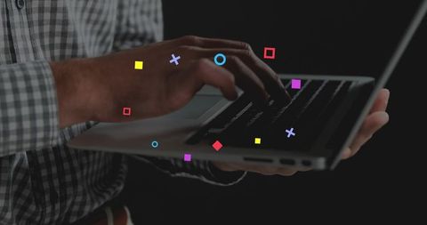 Typing on Laptop with Colorful Digital Icons Floating Over Hands and Dark Background