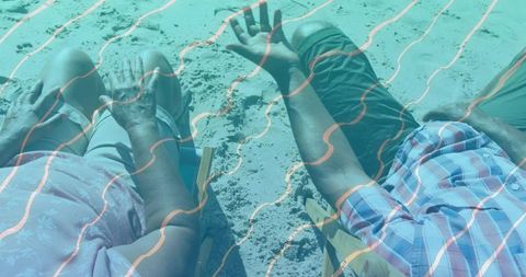 Senior couple relaxing on beach chairs by sandy shore with teal wave overlay