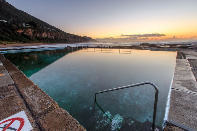 Serene coastal ocean pool with clear water and rocky shoreline at sunrise. Suitable for advertisements showcasing peaceful and tranquil settings, travel brochures, wellness retreats, or lifestyle blogs promoting relaxation and natural beauty.