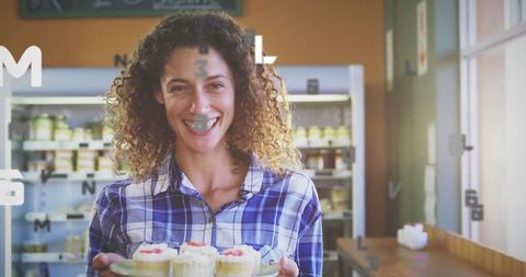 Cheerful Woman Holding Cupcakes in Cozy Café Setting