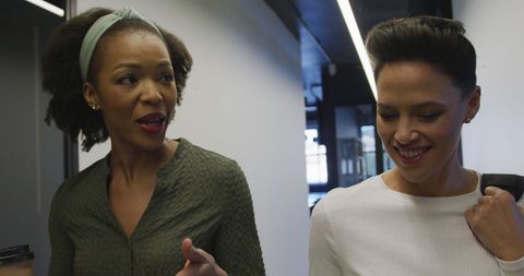 Diverse businesswomen conversing in modern office corridor