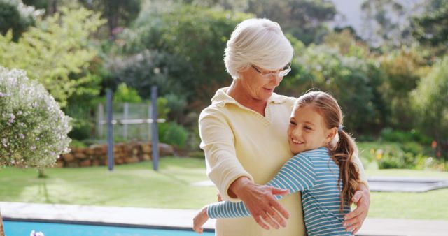 A senior Caucasian woman is embracing a young girl in a garden, with copy space. Their warm hug suggests a close family relationship, grandmother and granddaughter enjoying a sunny day outdoors.