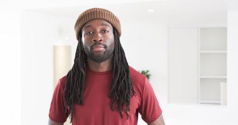 African American Man Wearing Beanie and Dreadlocks Facing Camera in Minimal Modern Space