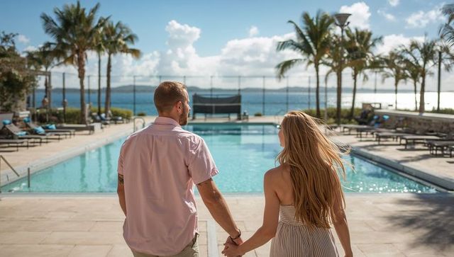 Couple walking hand in hand along resort pool deck toward ocean view, tropical vacation romance