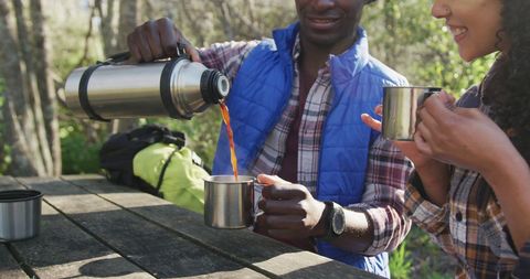 Diverse Couple Enjoying Tea During Hike in Scenic Countryside