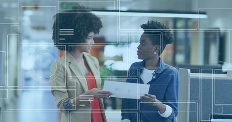 Two professionals discussing document in modern office environment