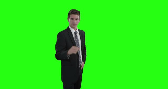 Businessman in professional attire posing confidently with hand gesture against a bright green screen background. Useful for presentations, marketing materials, and corporate communications where backgrounds can be edited or replaced.