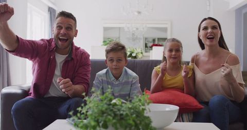 Excited Family Cheering Together on Cozy Living Room Sofa