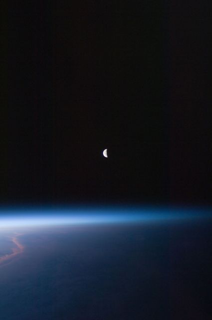 ISS028-E-030096(22 Aug. 2011) --- A last quarter moon appears at the center of this night time photo taken from the International   Space Station in Earth orbit on Aug. 22, 2011. A thin line of the planet's atmosphere and a small group of clouds are the other illuminated objects in the picture.