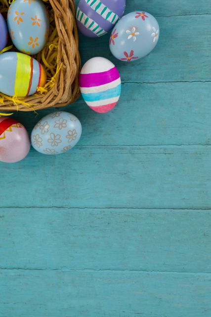 This image shows a collection of colorful Easter eggs arranged in a wicker basket on a wooden surface. Ideal for use in holiday-themed designs, greeting cards, social media posts, and advertisements related to Easter celebrations and springtime events.