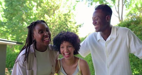 African american friends laughing and embracing in sunlit backyard casual summer gathering