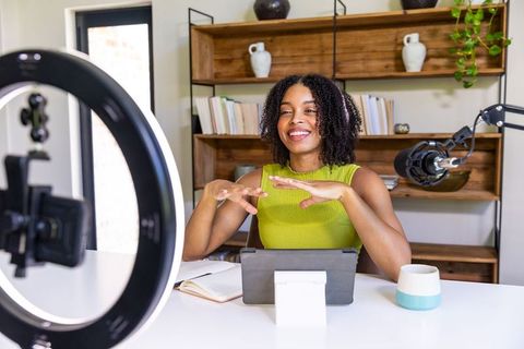 African american woman recording live stream with ring light, microphone and tablet