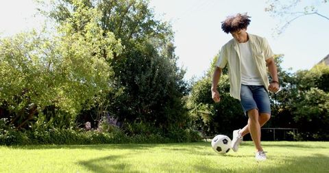 African American Man Playing Soccer in Sunlit Backyard