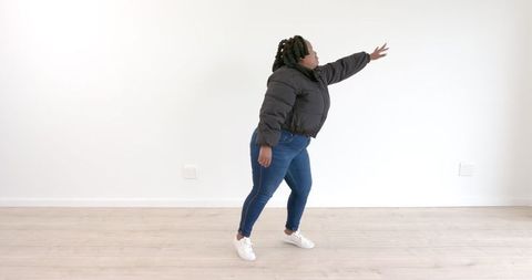 Woman in Denim and Puffer Jacket Reaching Out Energetically in Minimalist Room - Download Free Stock Images Pikwizard.com