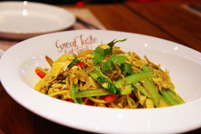 Dish of stir-fried noodles with chicken and various vegetables, garnished with cilantro. Ideal for promoting Asian restaurants, food blogs, and cookbooks. Highlights vibrant colors and appetizing presentation to attract food enthusiasts and culinary content creators.