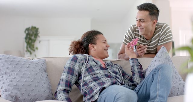 Same-sex couple enjoying quality time on couch with flowers - Download Free Stock Images Pikwizard.com