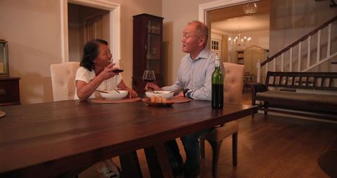 Senior Asian Couple Dining with Wine at Home During Evening