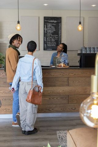 Couple ordering coffee from friendly african american barista at cozy modern cafe