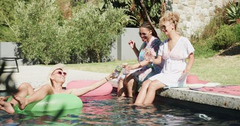 Diverse Friends Laughing and Toasting by Summer Poolside
