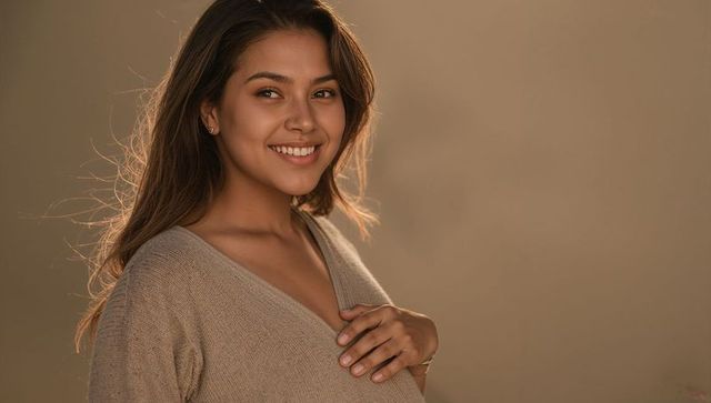 Smiling woman in knit v-neck sweater warm studio portrait with soft light and copy space