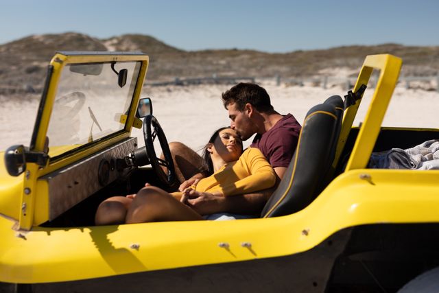 Happy caucasian couple sitting in beach buggy by the sea kissing. beach stop off on romantic summer holiday road trip.