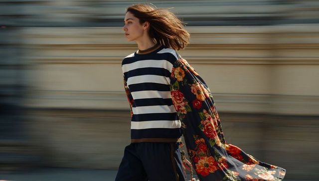 Young Woman Walking Urban Street Wearing Striped Sweater and Floral Coat, Motion Blur