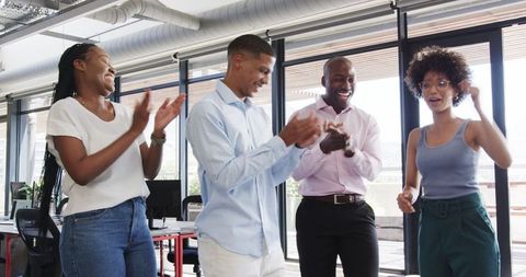 Happy colleagues applauding success in modern office space