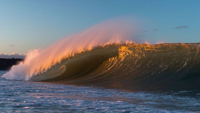 Dynamic golden hour wave hitting coastline