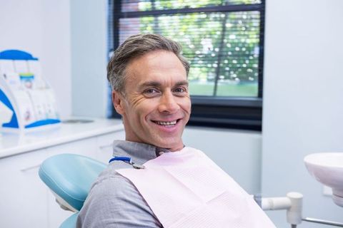 Smiling middle-aged man relaxing in dental office for checkup