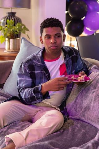 Teen Boy Enjoying Cake Sitting Living Room during Celebration