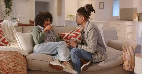 Couple Sharing Warm Drinks on Sofa in Cozy Open-Plan Living Room, Casual Home Moment