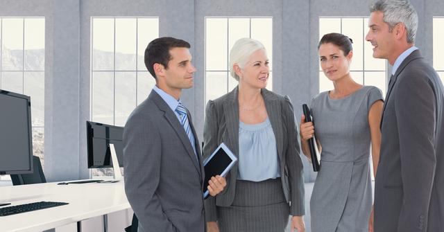 Group of business professionals standing and discussing in a modern office environment. Ideal for use in corporate presentations, business websites, teamwork and collaboration concepts, and professional networking materials.