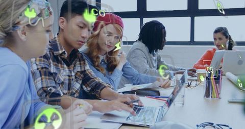 Collaborating creative team using laptops with augmented reality icons in modern workspace