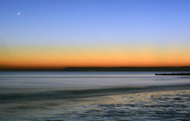 Serene Sunset Over Ocean With Crescent Moon - Download Free Stock Photos Pikwizard.com