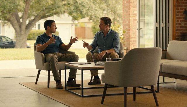 Two professionals collaborating in modern living room lounge with laptop and papers