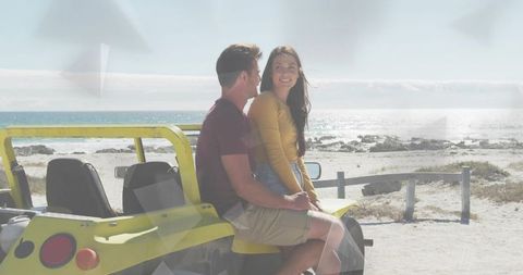 Couple enjoying dune buggy adventure on sunlit beach coastline during romantic getaway