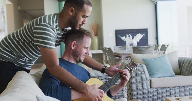 Two men bonding while playing guitar at home - Download Free Stock Images Pikwizard.com