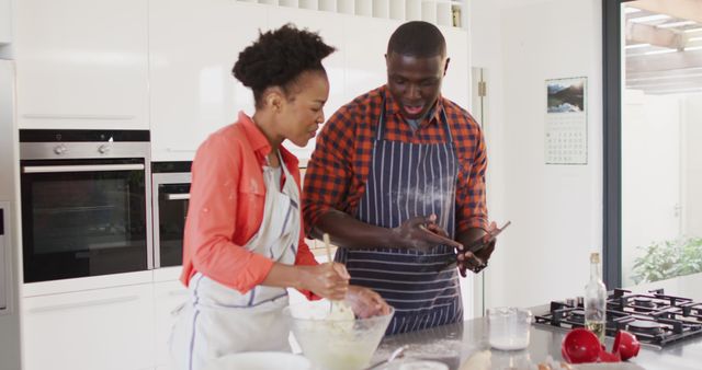 Image of happy african american couple baking together in kitchen. Love, relationship and spending quality time together concept.