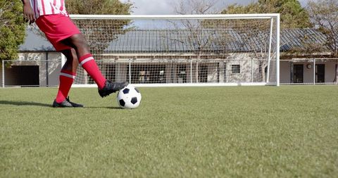 Soccer player practicing on turf field with goal in background