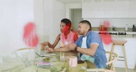 Couple collaborating on home design using laptop and fabric swatches in modern kitchen