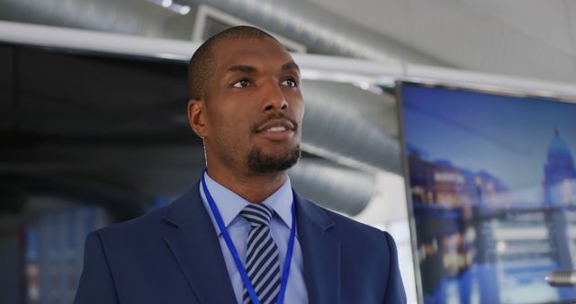African American businessman confidently presenting at a conference while wearing a blue suit and tie. Useful for depicting business environments, leadership, corporate presentations, professional settings, and workplace meetings.