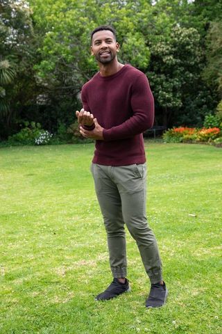 Man in Burgundy Sweater Relaxing in Lush Green Garden