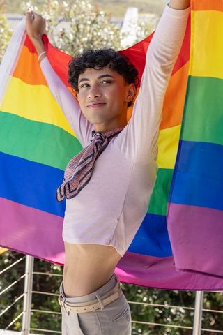Person Celebrating LGBTQ Pride Holding Rainbow Flag Outdoors