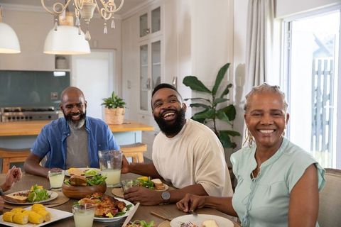 Joyful Family Gathering Around Dining Table with Food in Cozy Kitchen