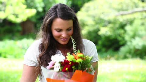 Smiling Woman with Floral Bouquet Enjoying Nature in Park