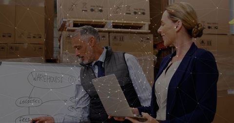 Business professionals discussing logistics in warehouse with technology