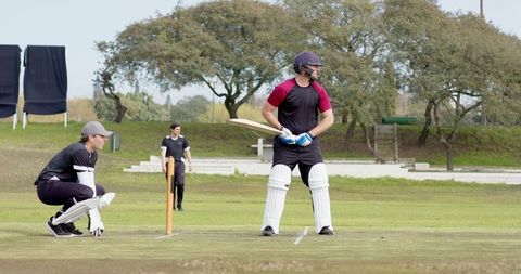 Cricketers Competing in Outdoor Match on Green Field